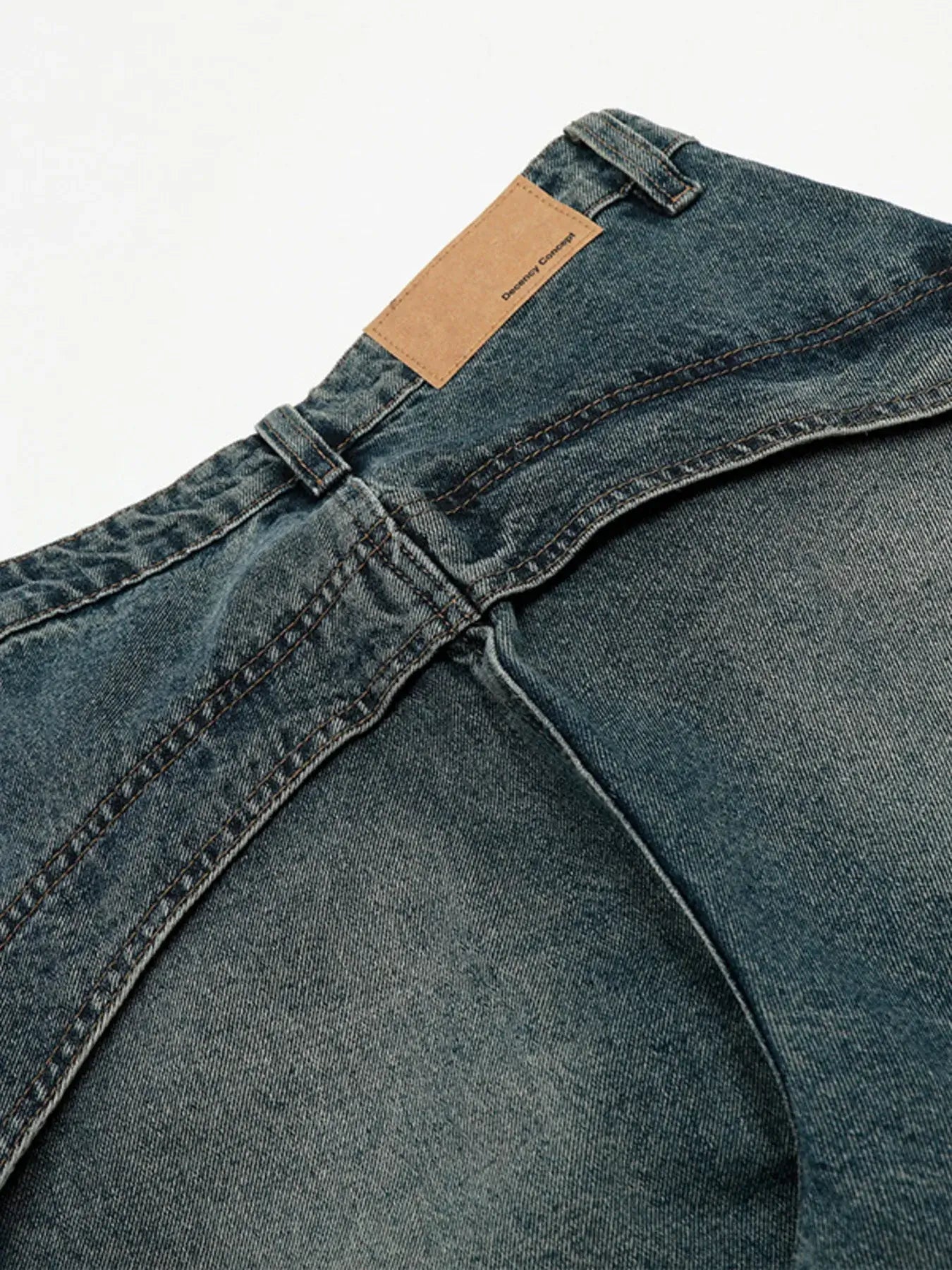 Close-up of vintage washed wide leg baggy jeans for men, showing seam detailing and waistband label.