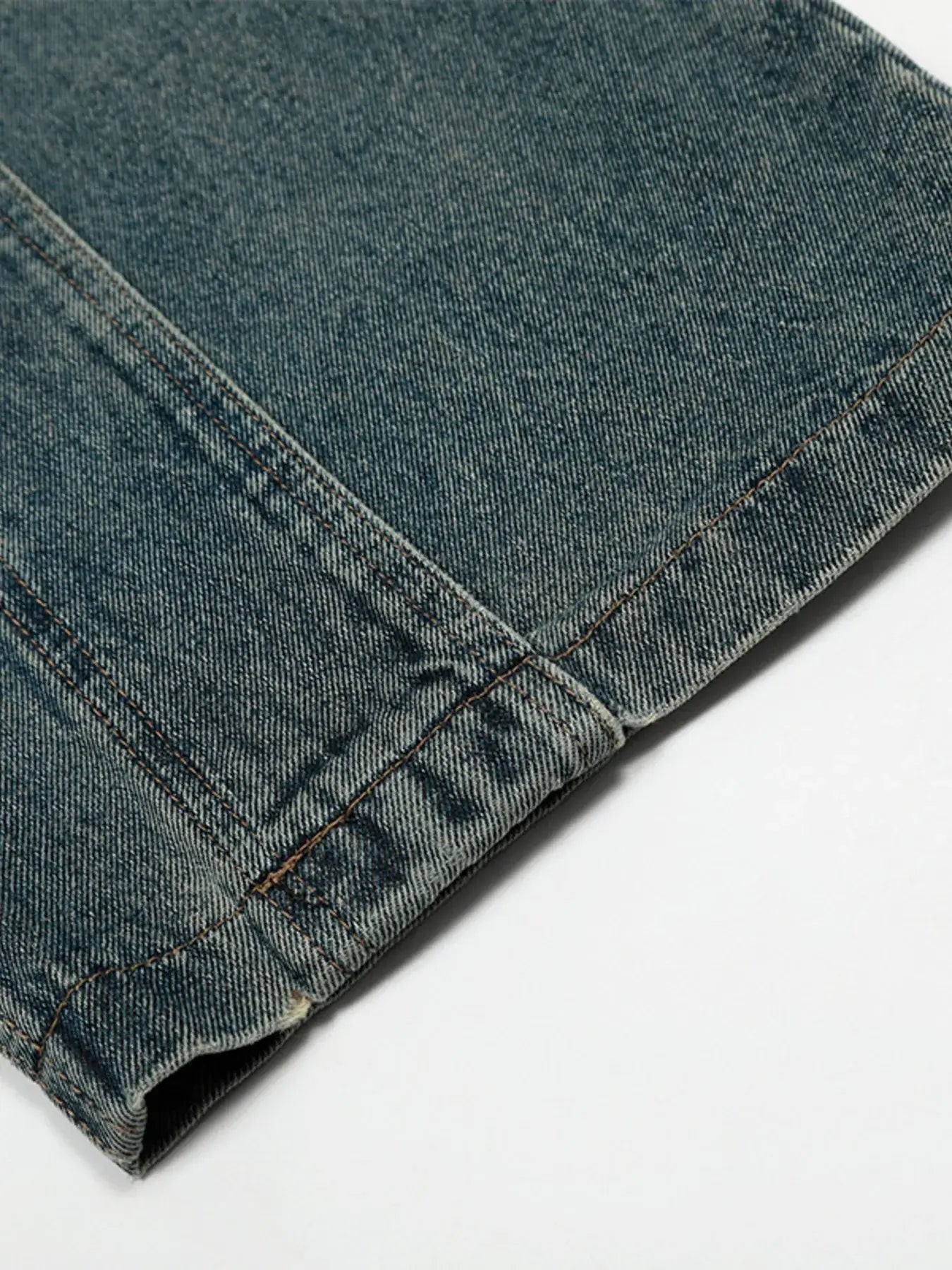 Close-up of vintage washed wide leg baggy jeans showing distressed detailing and seam for added texture.